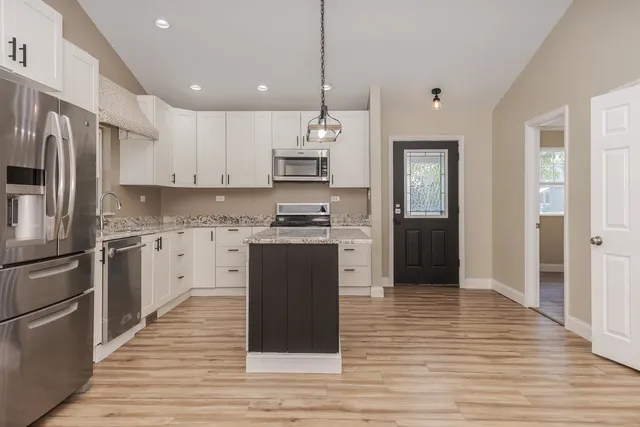a kitchen with granite countertop a refrigerator stove top oven and sink