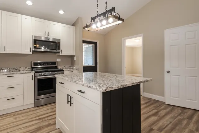 a kitchen with stainless steel appliances granite countertop a stove top oven a sink and dishwasher with wooden floor