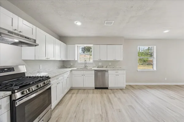 a kitchen with a stove a sink and wooden floor