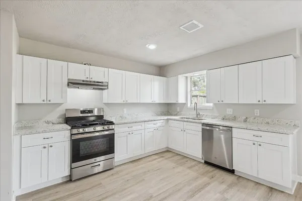 a kitchen with granite countertop white cabinets and white appliances