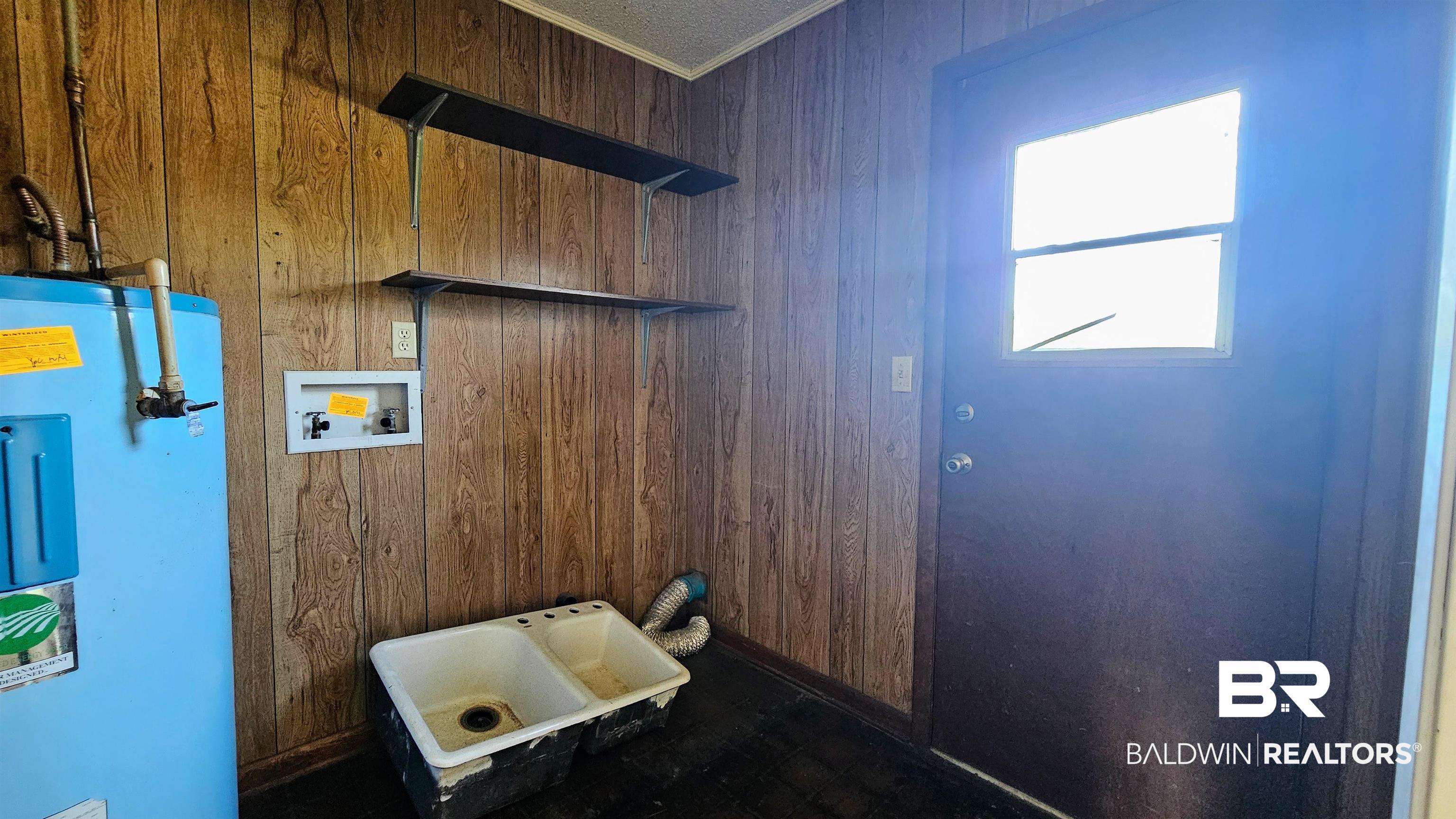 18824 Highway 41 Brewton, AL 36426 - Photo 8 of 40 Utility space featuring wood-finish wall paneling, a double basin utility sink, and wall-mounted shelving