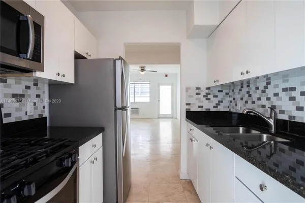 a kitchen with granite countertop a sink stove and refrigerator