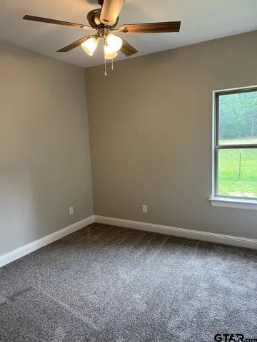 en empty room with windows and chandelier fan