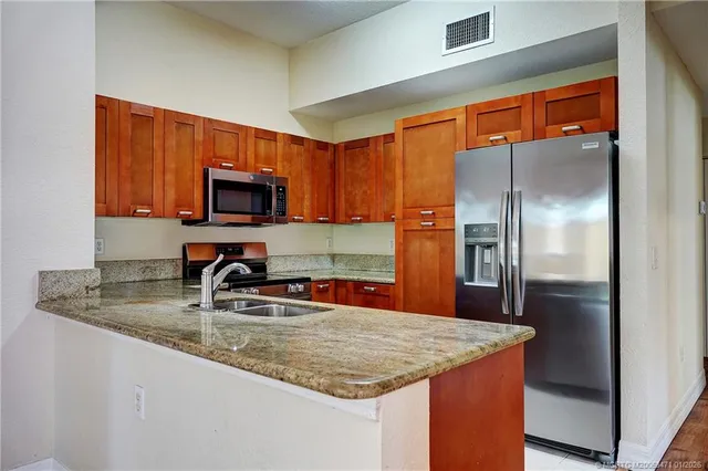 a kitchen with stainless steel appliances granite countertop a refrigerator a stove top oven a sink and dishwasher