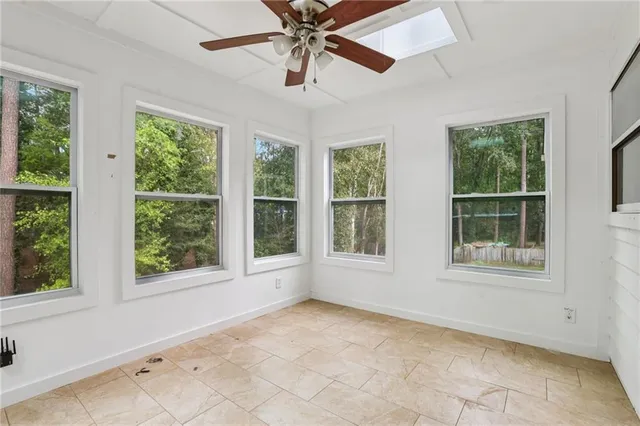 an empty room with chandelier fan and windows
