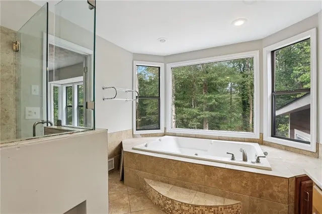 a bathroom with a tub a sink and a large window