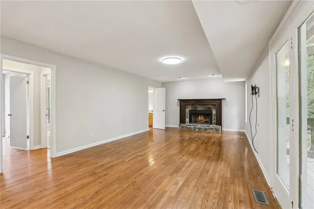 a view of empty room with wooden floor and fireplace