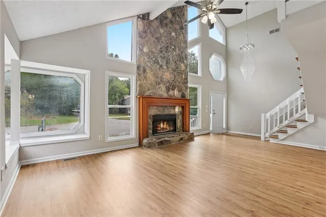 a view of an empty room with wooden floor fireplace and a window