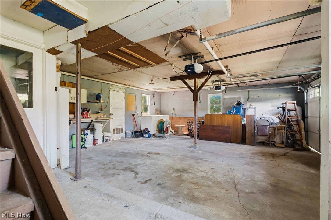 759 Runkle Avenue Ashtabula, OH 44004 - Photo 23 of 40 Spacious garage with concrete flooring, exposed ceiling joists, two garage door openers, multiple windows, and a built-in workbench