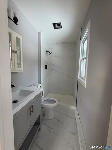 a bathroom with a granite countertop sink a toilet and shower