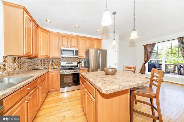 a kitchen with stainless steel appliances kitchen island granite countertop a stove a sink and a refrigerator