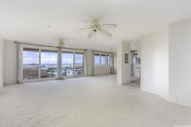 an empty room with chandelier fan and windows