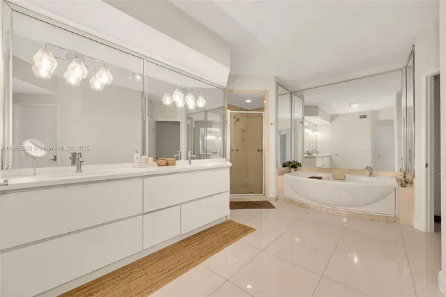 a bathroom with a double vanity sink a large mirror and shower