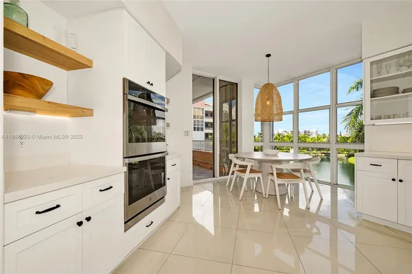 a dining hall with stainless steel appliances kitchen island granite countertop a table and chairs in it