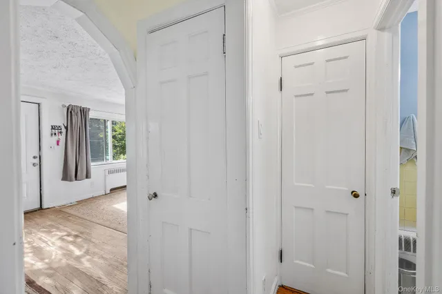 a view of a hallway with wooden floor and a bathroom
