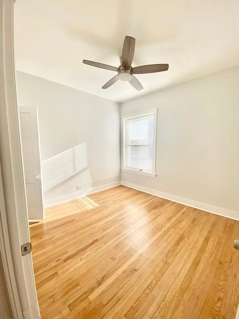 4100 West Henderson Street, Unit 1 Chicago, IL 60641 - Photo 5 of 8 an empty room with wooden floor and a ceiling fan