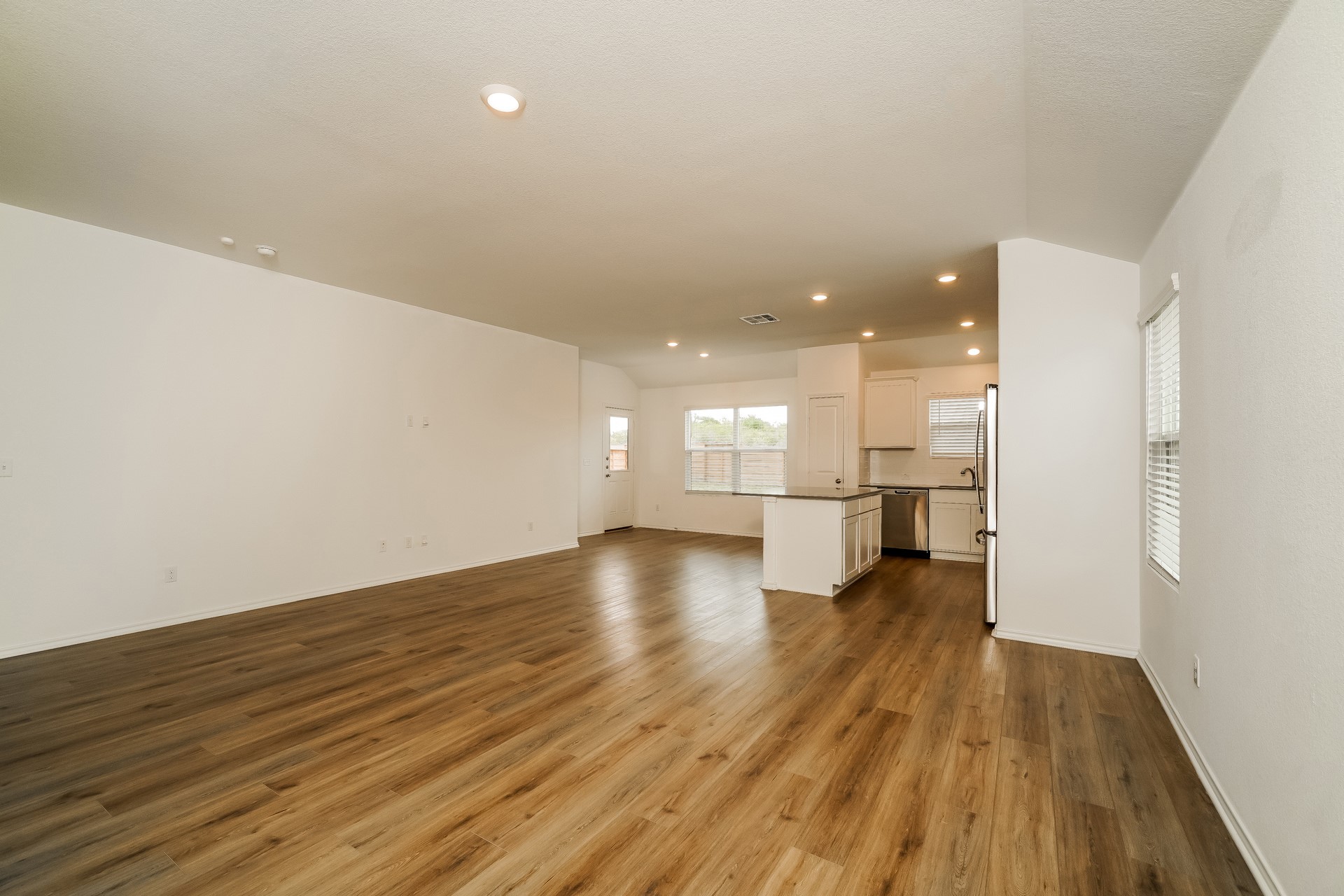 341 Madrid Kyle, TX 78640 - Photo 27 of 27 An open floorplan seamlessly connects the living space to a modern kitchen, featuring recessed lighting and durable laminate flooring.