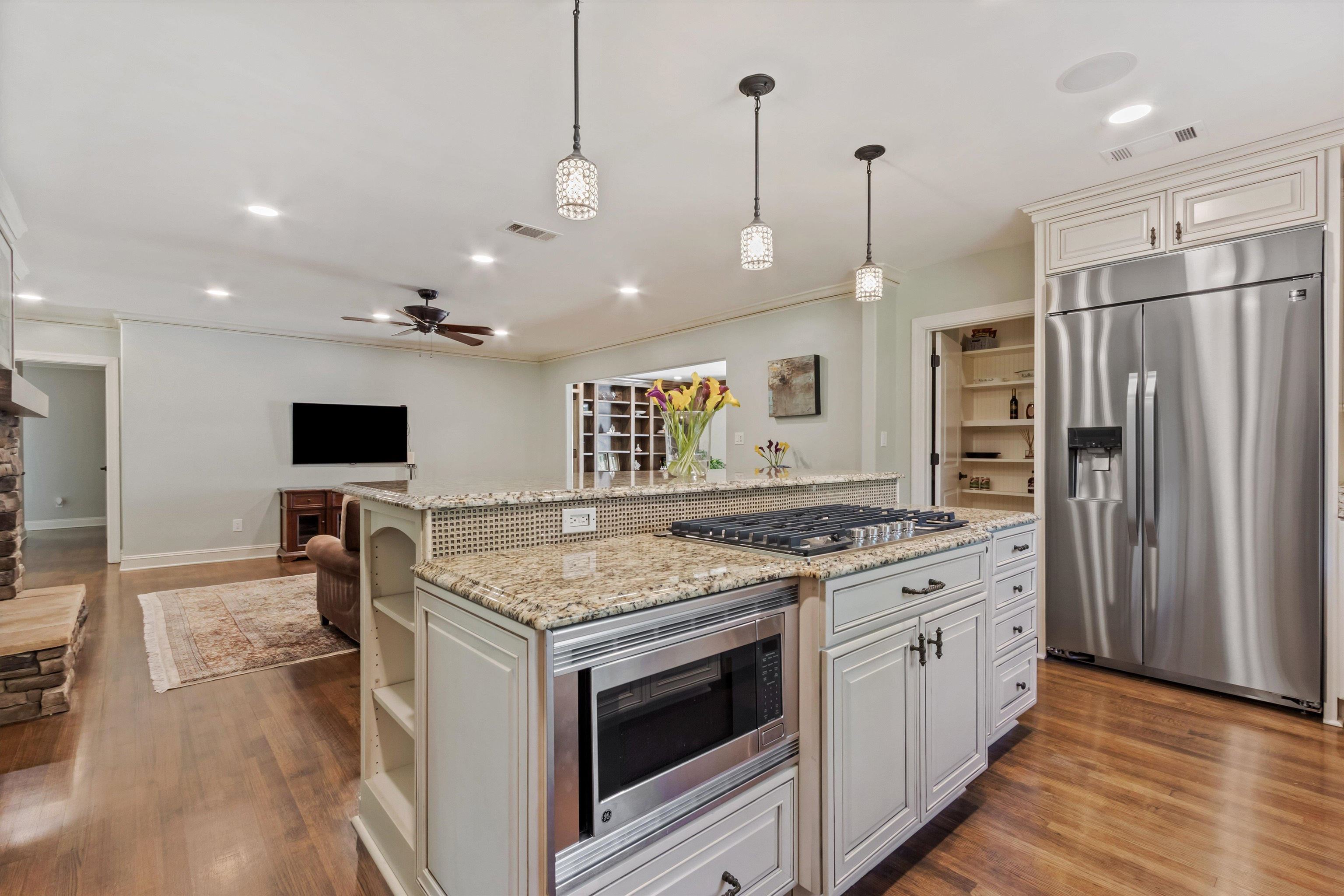 5302 South Angela Road Memphis, TN 38120 - Photo 4 of 40 Kitchen island featuring a built-in microwave, gas cooktop, and granite countertops