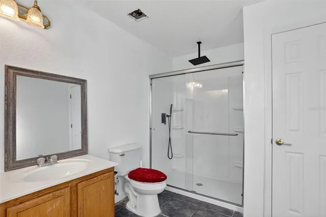 a bathroom with a granite countertop sink mirror shower and toilet