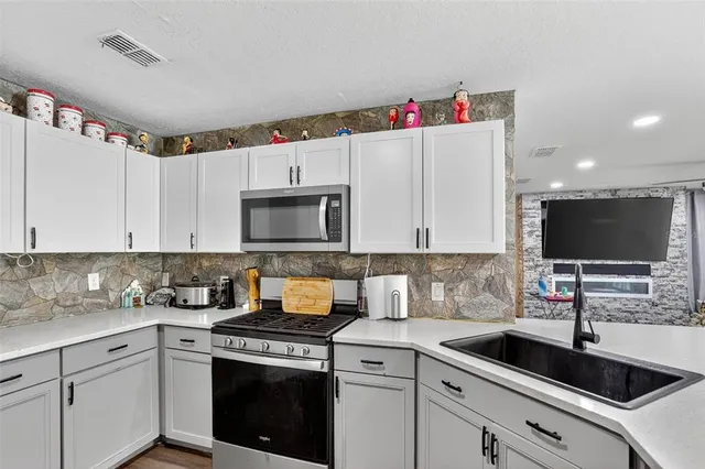 a kitchen with a sink stove top oven and microwave