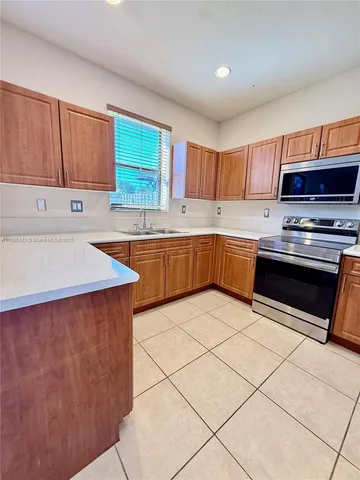 a kitchen with granite countertop a refrigerator and a stove top oven