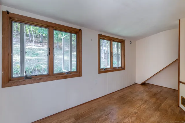 a view of an empty room with wooden floor and a window