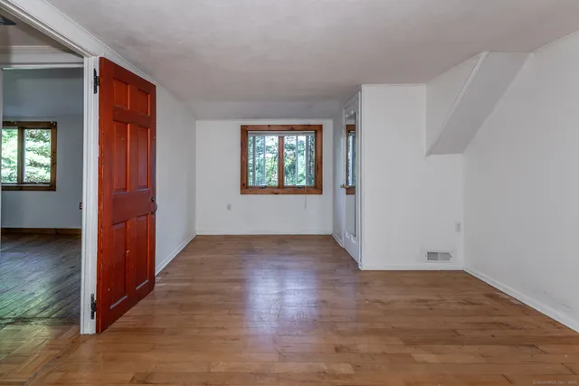 an empty room with wooden floor and windows