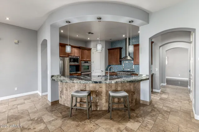 a kitchen with stainless steel appliances granite countertop a refrigerator a stove and a sink with wooden floor