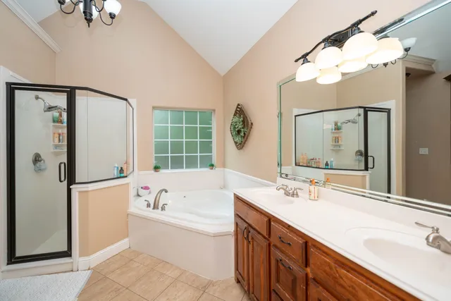 a bathroom with a tub a sink double vanity and a mirror