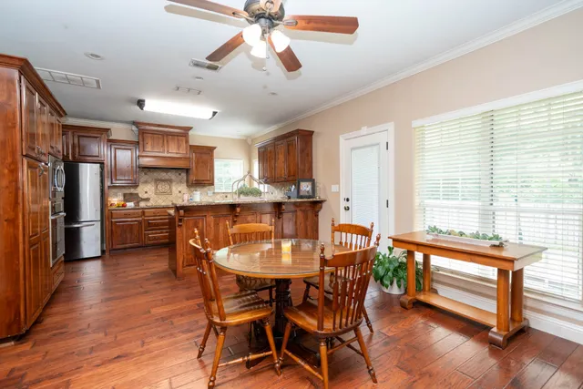 a dining room with stainless steel appliances kitchen island granite countertop a table chairs and a refrigerator