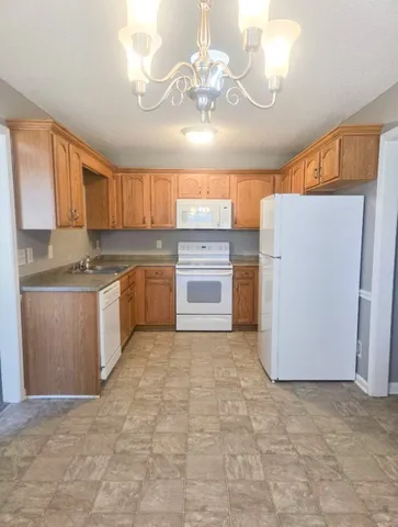 a kitchen with granite countertop a refrigerator a stove a microwave oven cabinets and a dining table