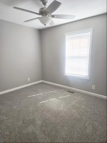 an empty room with a window and a fan