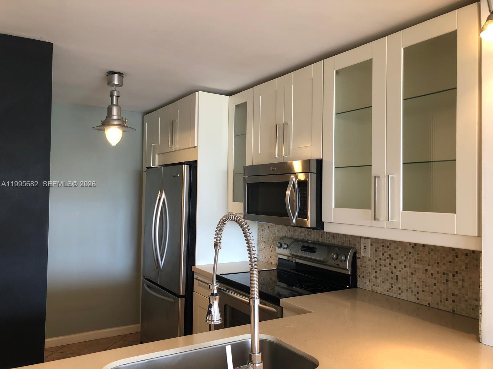 1401 Bay Road, Unit 412 Miami Beach, FL 33139 - Photo 5 of 9 a kitchen with stainless steel appliances granite countertop a refrigerator a stove and a sink with wooden floor