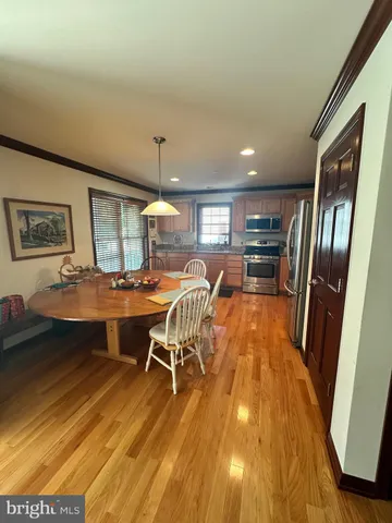 a dining room with wooden floor a chandelier a wooden table and chairs
