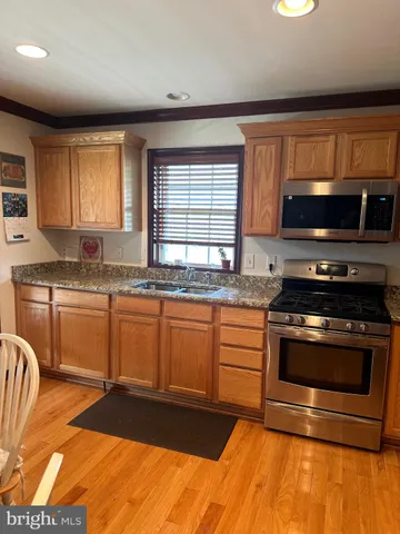 a kitchen with granite countertop a stove a sink and a microwave