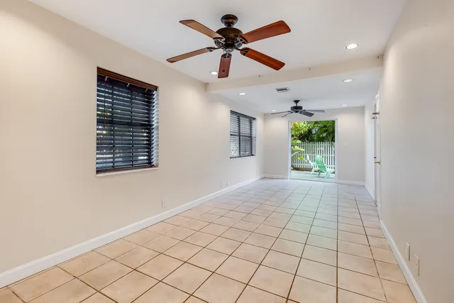 a view of an empty room and a ceiling fan and window