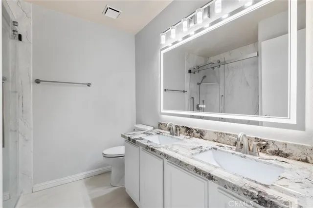 a bathroom with a granite countertop sink a toilet and a mirror