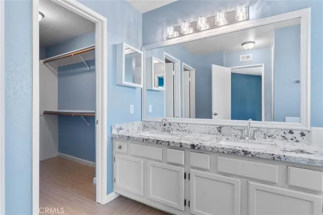a bathroom with a granite countertop double vanity sink and a mirror