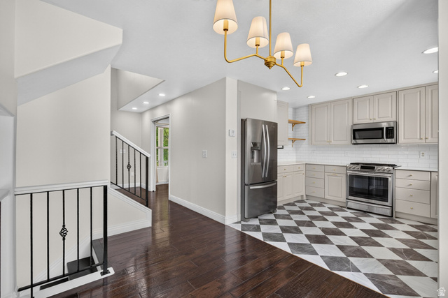 2223 North Pointe Meadow Loop Lehi, UT 84048 - Photo 11 of 56 Modern kitchen featuring stainless steel appliances, light-toned cabinetry, subway tile backsplash, and a striking black and white checkered floor