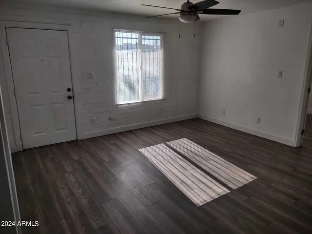 an empty room with wooden floor cabinet and windows