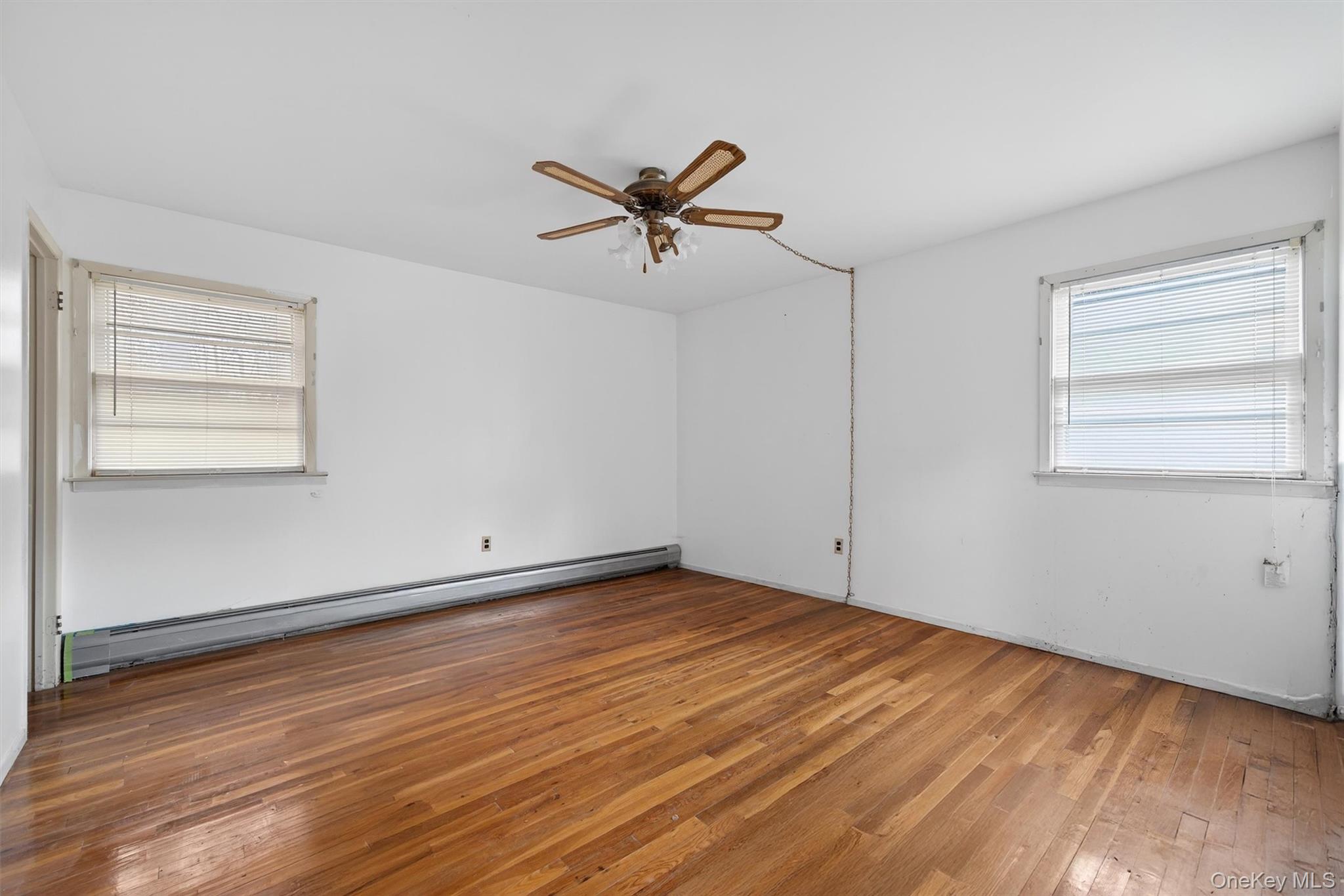 53 Mallory Road Spring Valley, NY 10977 - Photo 19 of 33 Unfurnished room featuring baseboard heating, light wood-type flooring, plenty of natural light, and a ceiling fan