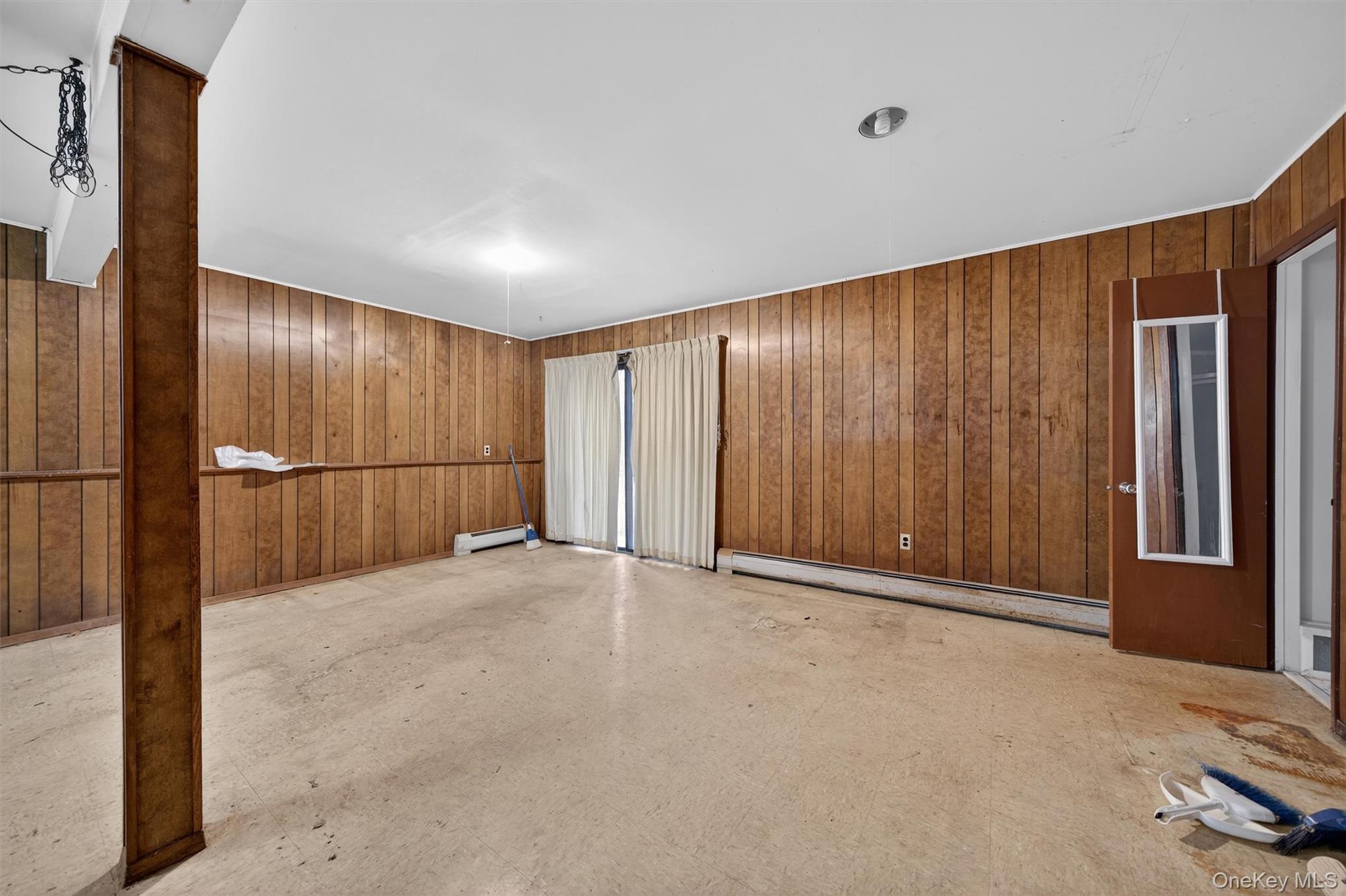 53 Mallory Road Spring Valley, NY 10977 - Photo 22 of 33 Spare room with wood walls, a baseboard heating unit, and concrete flooring