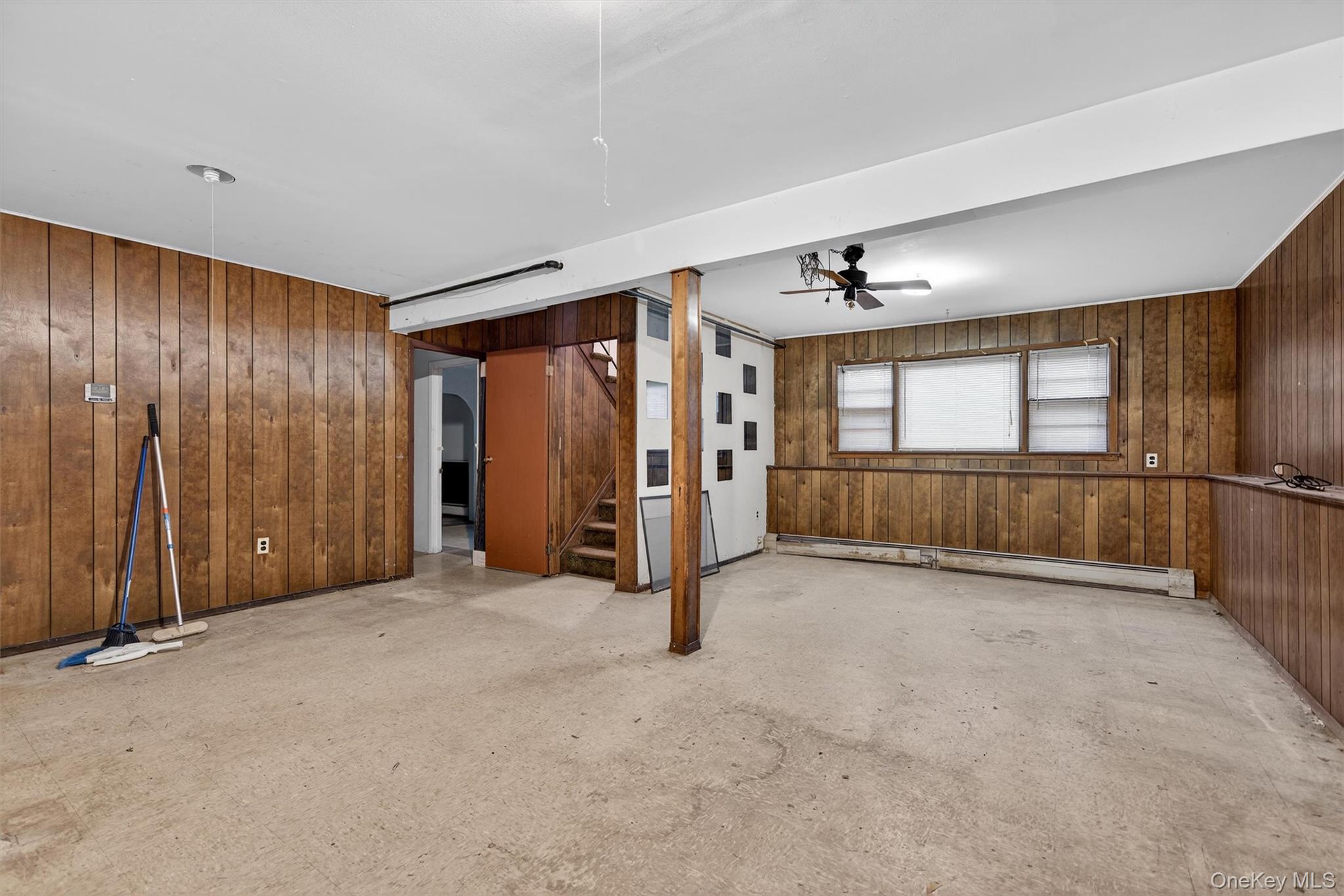 53 Mallory Road Spring Valley, NY 10977 - Photo 23 of 33 Unfurnished room featuring wooden walls, baseboard heating, ceiling fan, and unfinished concrete flooring