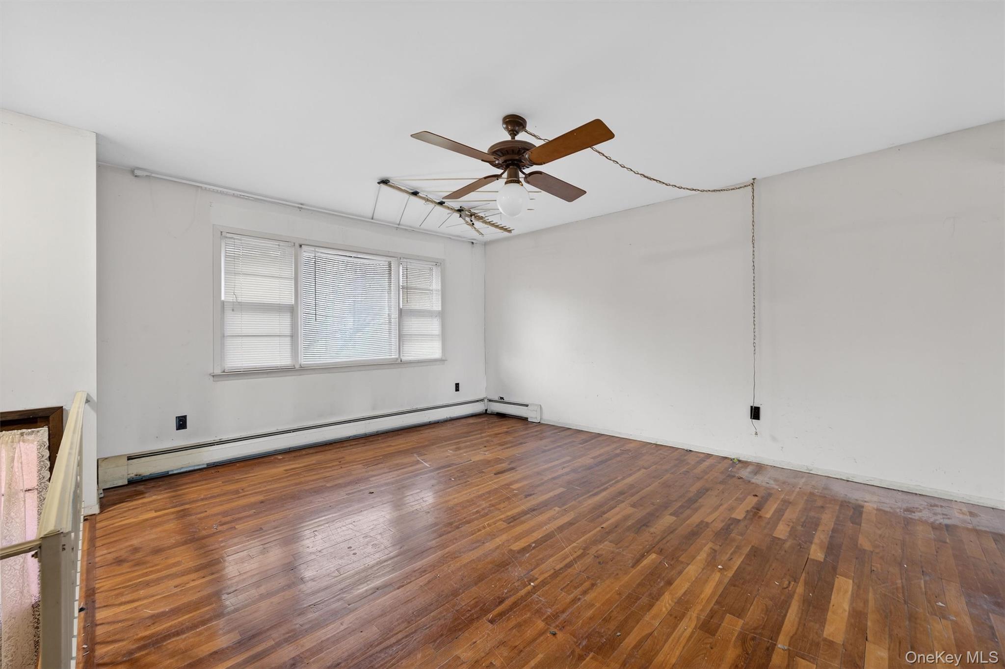 53 Mallory Road Spring Valley, NY 10977 - Photo 5 of 33 Spare room featuring wood-type flooring, a baseboard heating unit, and a ceiling fan