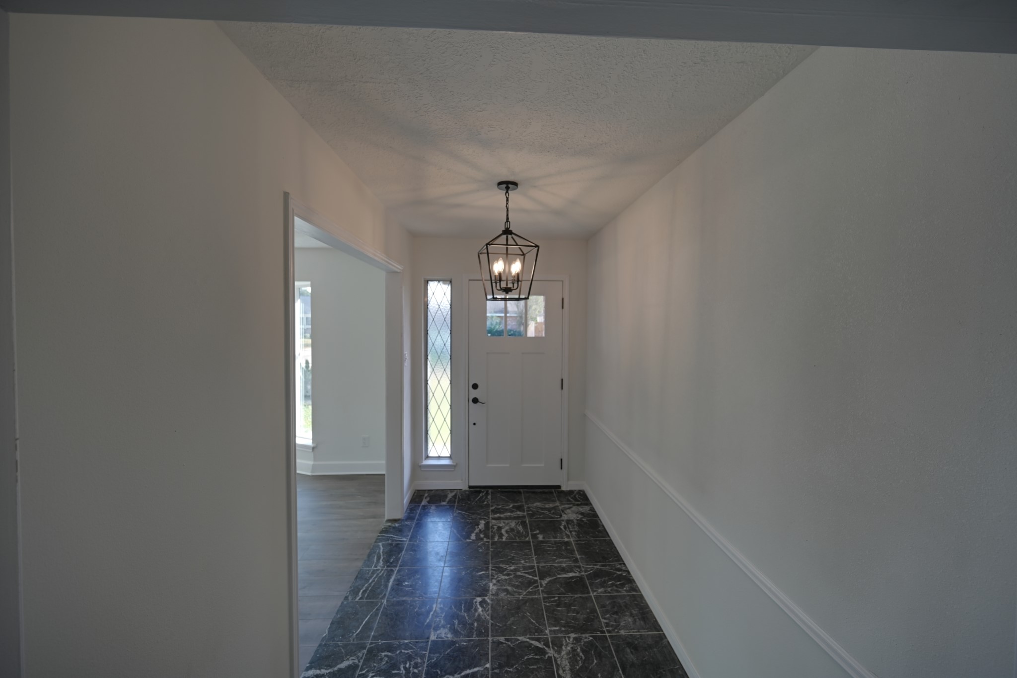 10410 Cook Road Houston, TX 77099 - Photo 2 of 14 a view of a hallway with wooden floor and a chandelier