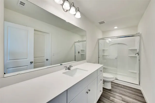a bathroom with a double vanity sink a toilet and shower