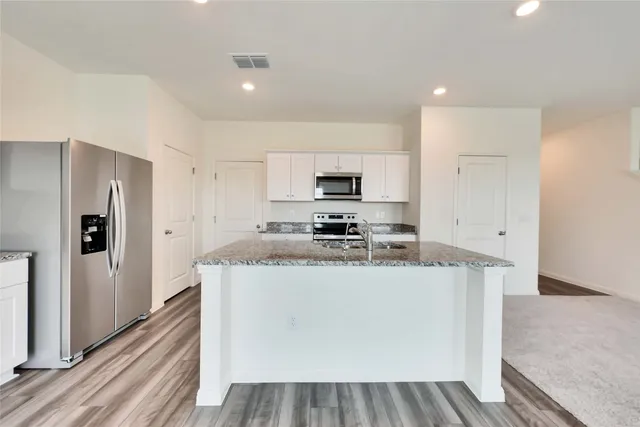 a kitchen with stainless steel appliances granite countertop a refrigerator a stove and a sink