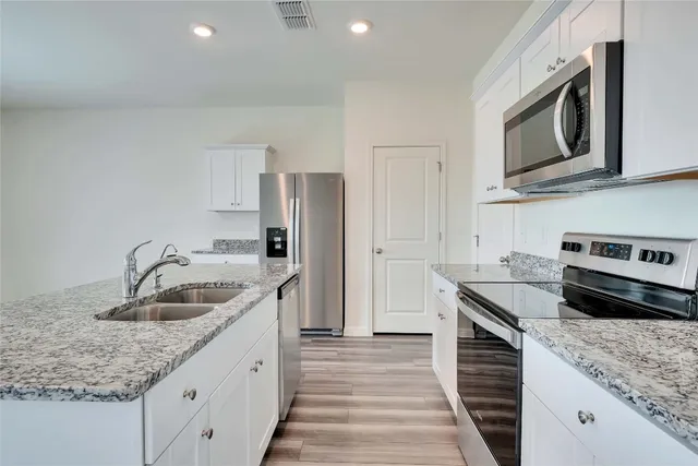 a kitchen with stainless steel appliances granite countertop a sink stove and refrigerator