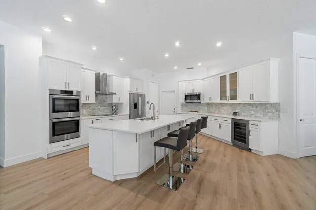 a kitchen with stainless steel appliances kitchen island granite countertop a large center island and a stove top oven