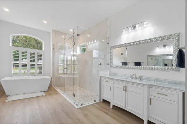 a spacious bathroom with a granite countertop sink mirror and bathtub
